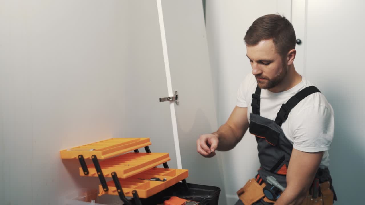 Close-up portrait of a young man in work uniform assembling furniture