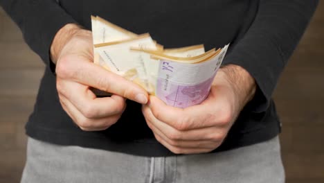 cerca de un joven en jeans contando mucho dinero, estático