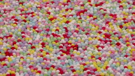 angled view. macro shooting of small colorful sprinkles sugar candies rotating. background.