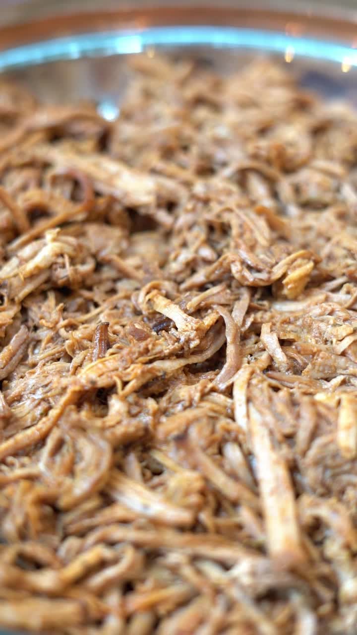 Shredded, tender cooked meat with a juicy, seasoned texture, close up shot