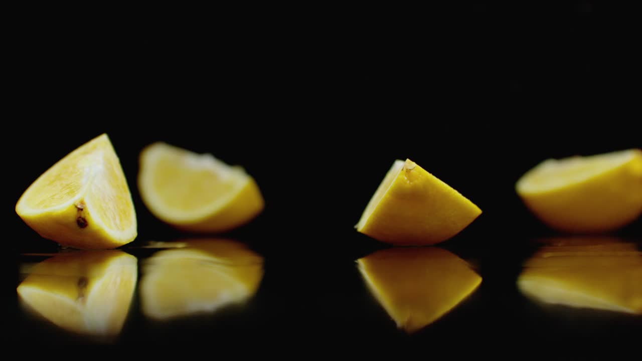 맛있는 노란색 레몬을 4 부분으로 나누고, 어두운 배경에 느린 동작으로 물을 뿌려주세요.