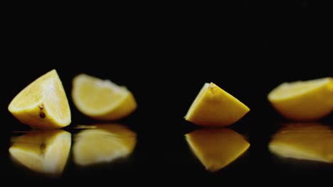 limón amarillo en rodajas jugosas caen en 4 partes de vidrio con salpicaduras de agua en cámara lenta sobre un fondo oscuro.