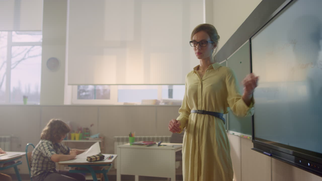 учитель объясняет урок. девочка рисует задание на интерактивной цифровой доске