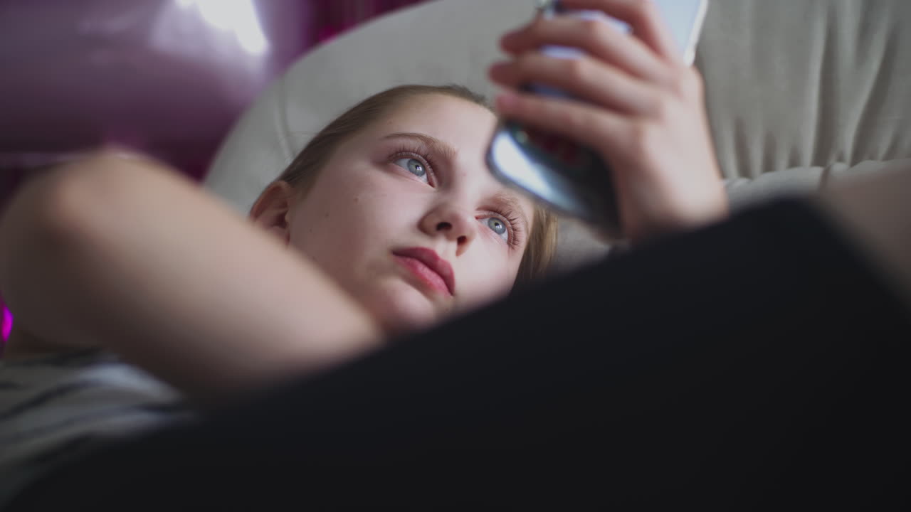 Teenage girl using a smartphone and eating a cracker