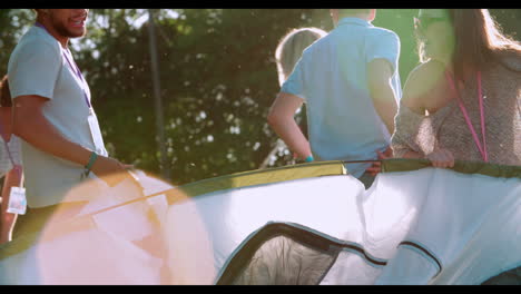 group of young friends pitching tents on camping holiday