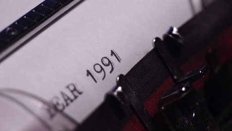 año 1991, escribiendo en papel blanco en una máquina de escribir de época, de cerca
