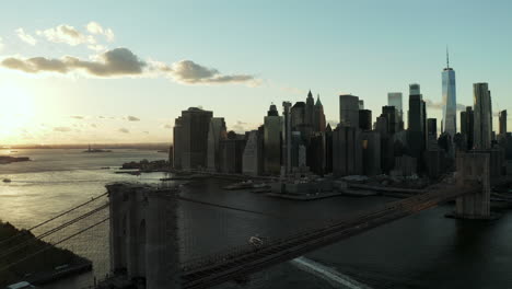 Volar-Sobre-El-Puente-De-Brooklyn-Con-El-Horizonte-Del-Centro.-Siluetas-De-Rascacielos-De-Oficinas-Contra-El-Cielo-Del-Atardecer.-Manhattan,-Ciudad-De-Nueva-York,-Estados-Unidos