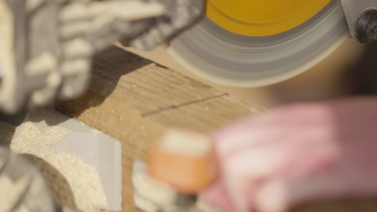 Slow motion macro shot of a blade spinning and cutting through wooden decking boards