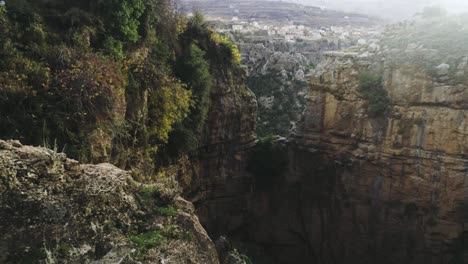 Aerial-view-of-hiker-walk-towards-cliff-mountain-edge-in-Lebanon,-forward,-day