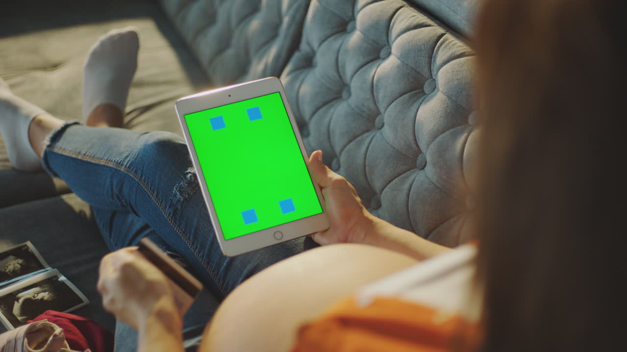Pregnant woman using a tablet for online shopping
