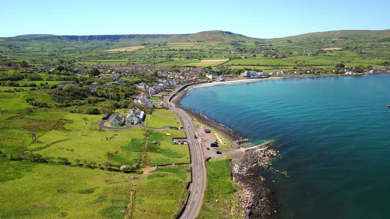 Wide, reversing overhead aerial video of the Antrim Coastal Route on a bright and sunny day. Filmed in Ballygally in 4K, 60FPS and with Rec800 color.