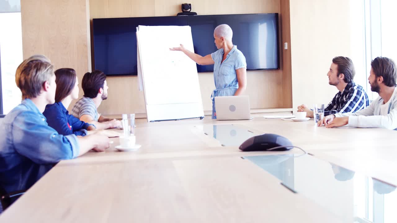 mujer dando una presentación a sus colegas en la sala de conferencias
