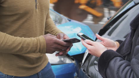 dos automovilistas intercambiando detalles de seguro en el teléfono móvil después de un accidente automovilístico