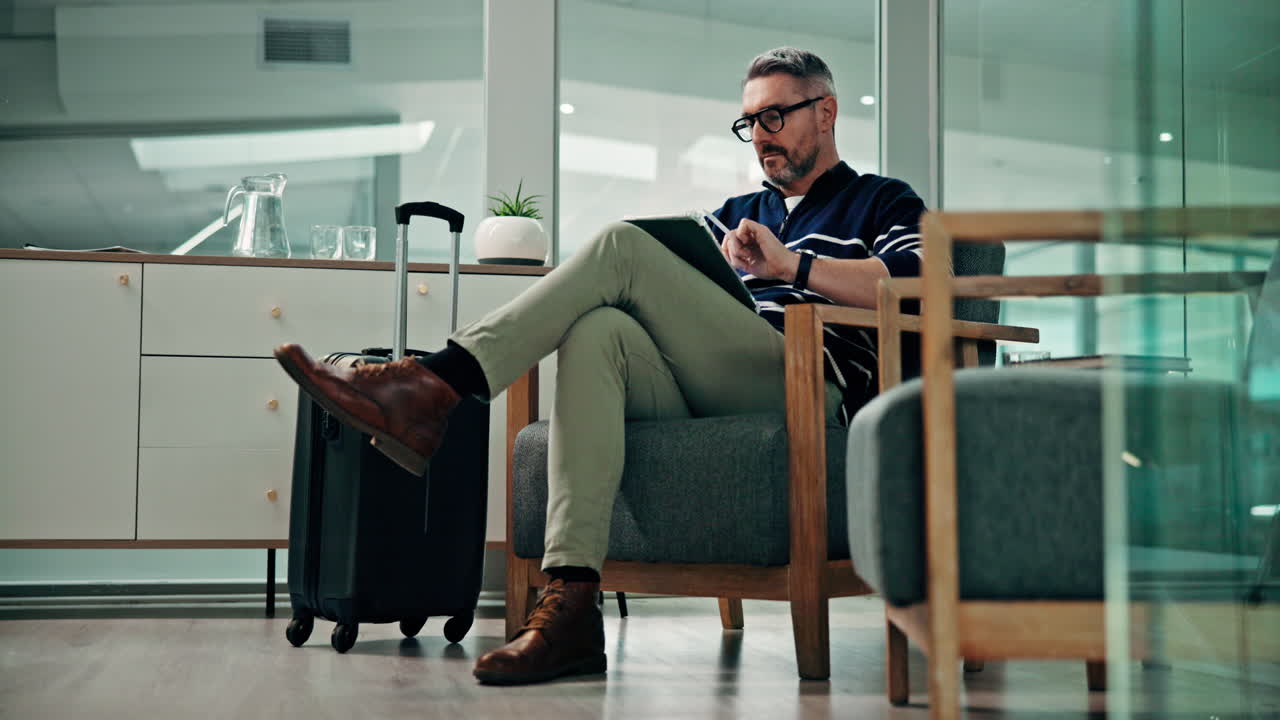 Man with Luggage Using Tablet in Waiting Area