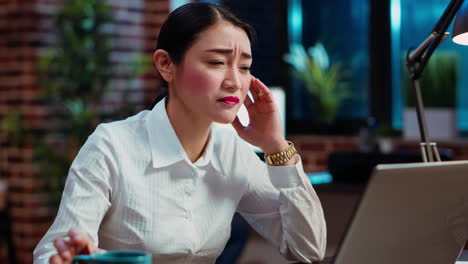 exhausted worker working overnight, typing on laptop, drinking coffee