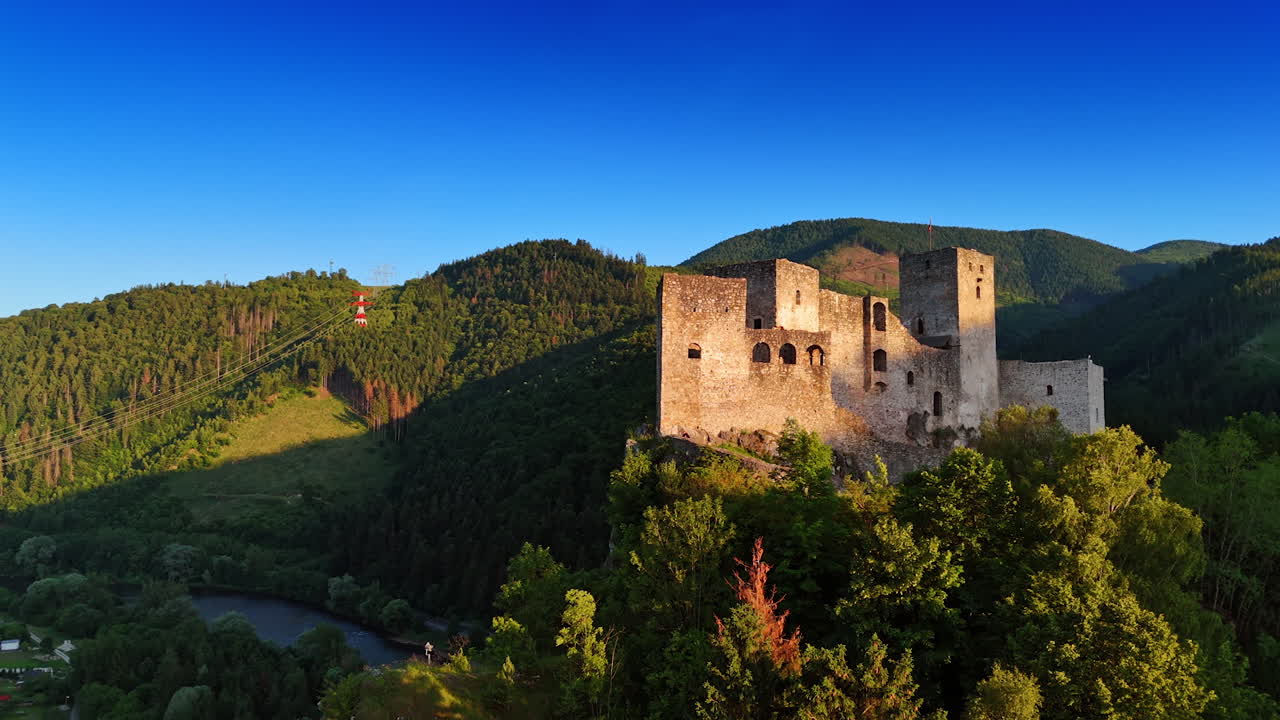 Let vzhůru ke skále s hradem Strečno na vrcholu. Zelené hory v pozadí. Slovenské památky.