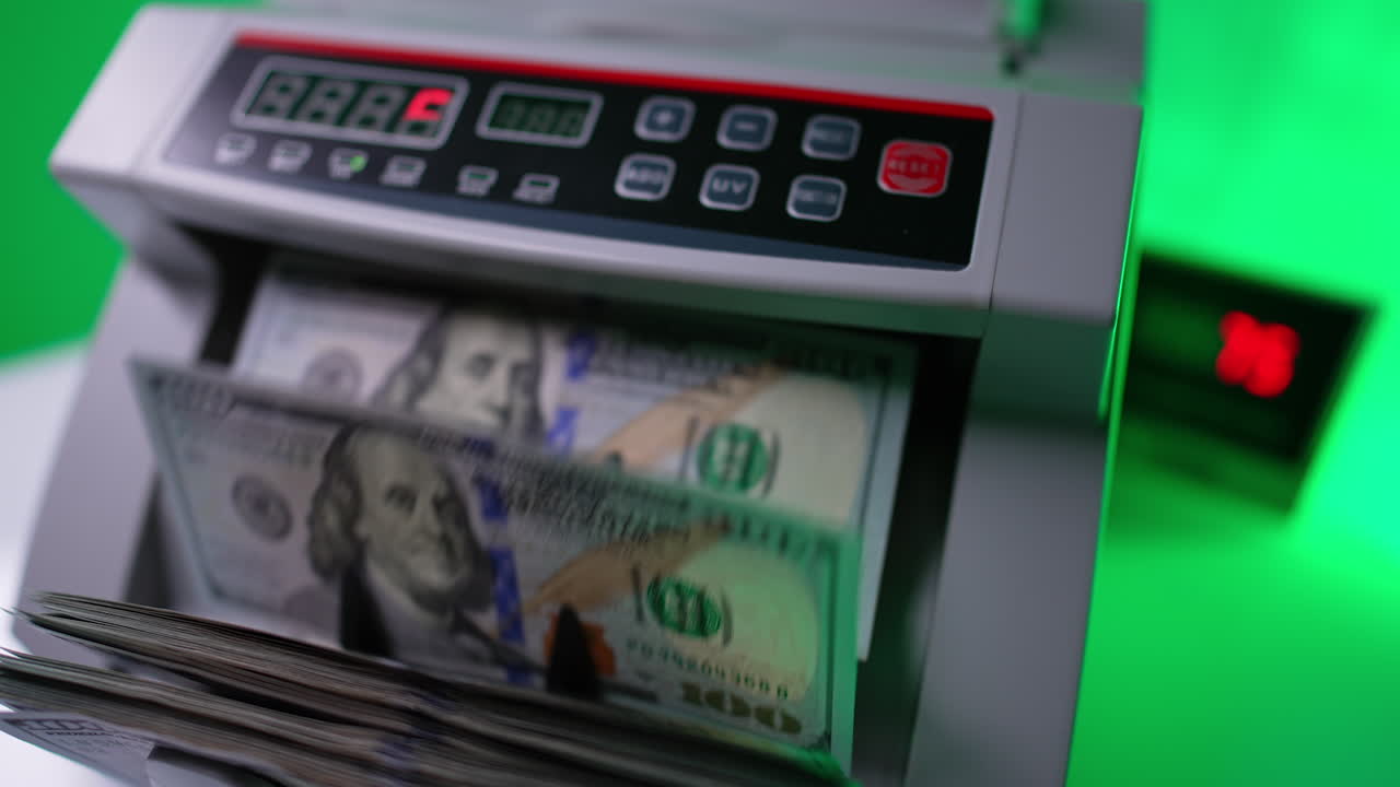 One hundred dollar bills are counted in cash counting machine. Benjamin Franklin banknotes are quickly rotated in equipment. Close up.