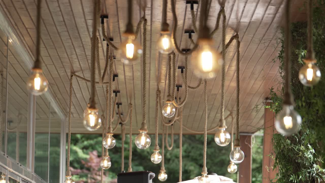 Vintage Edison bulbs hanging from ropes on a wooden ceiling in rustic decor