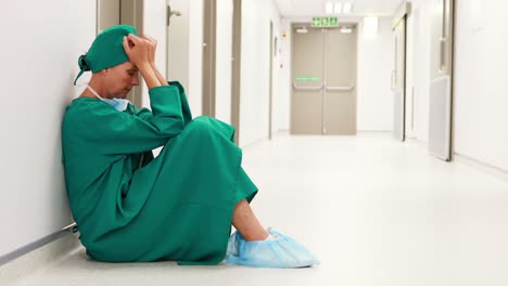 tensed female surgeon sitting in corridor