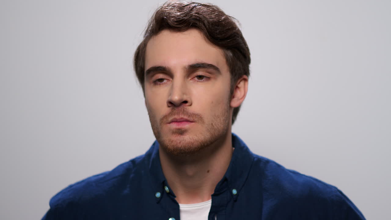 Angry man looking at camera. Displeased guy gesturing with hands in studio