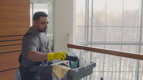 arabic cleaning man carrying a cleaning cart inside an office building