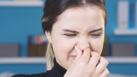 disgusted by the smell, young woman covers her nose.