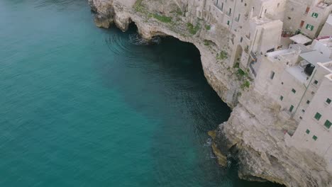 Imágenes-Panorámicas-Aéreas-Del-Mar-Azul-Chocando-Contra-Los-Acantilados-En-Polignano-A-Mare,-Italia