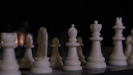 Zeitlupenschwenk-über-Weißen-Schachfiguren,-Die-Vor-Einem-Dunklen-Hintergrund-In-Bereitschaftsposition-Aufgereiht-Sind