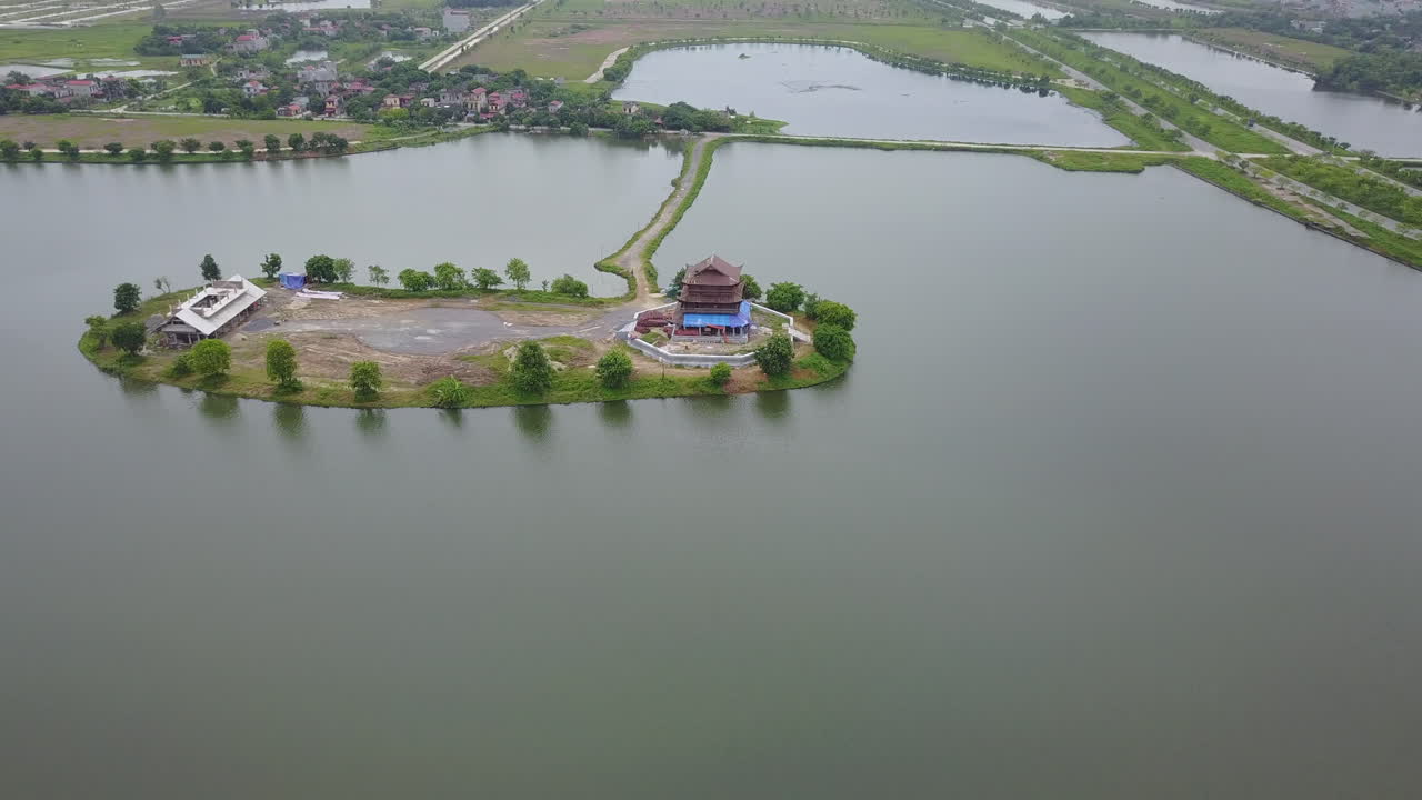 Experience a gentle tilt-down aerial view of the small island that houses Dinh Thanh Cao Son in Trang An, Ninh Binh, Vietnam, showcasing the temple's unique island.