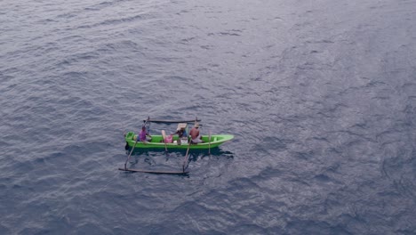 Drone-shot-of-small-green-fishing-boat-at-calm-sea-during-sunrise,-Indonesia