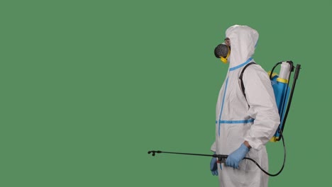 un virólogo en uniforme de protección camina y desinfecta el área usando un lavador de alta presión en una pantalla verde, llave de croma. concepto de prevención de coronavirus. cámara lenta. primer plano