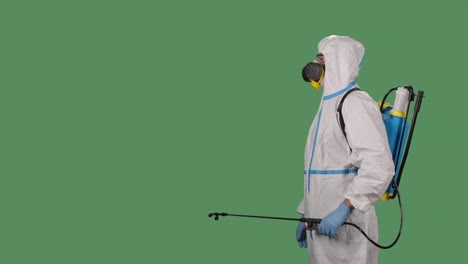 virologist in protective uniform walks and disinfects the area using a high pressure washer on a green screen, chroma key. coronavirus prevention concept. slow motion. close up