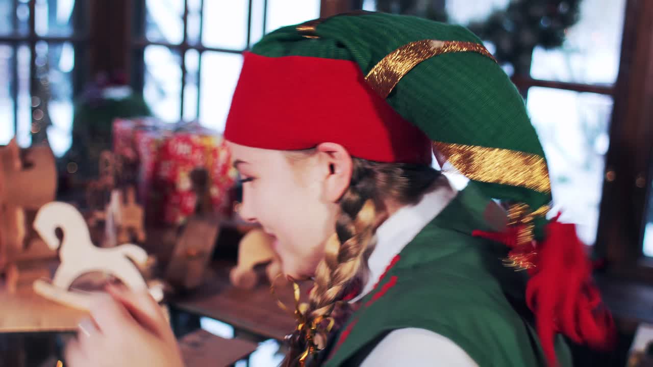 Joyful emotions of an elf girl. The girl at the table with New Year's toys opens Christmas letters to Santa Claus