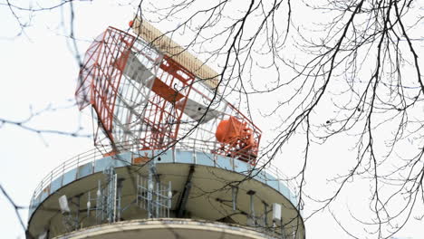 Close-up-of-the-radar-tower-at-Neunkirchner-Höhe,-Darmstadt,-Odenwald,-during-winter-with-tree-branches-in-front