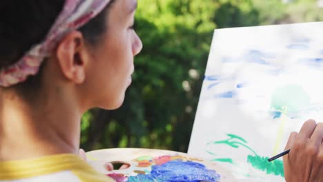 mixed race woman painting on canvas in the balcony at home