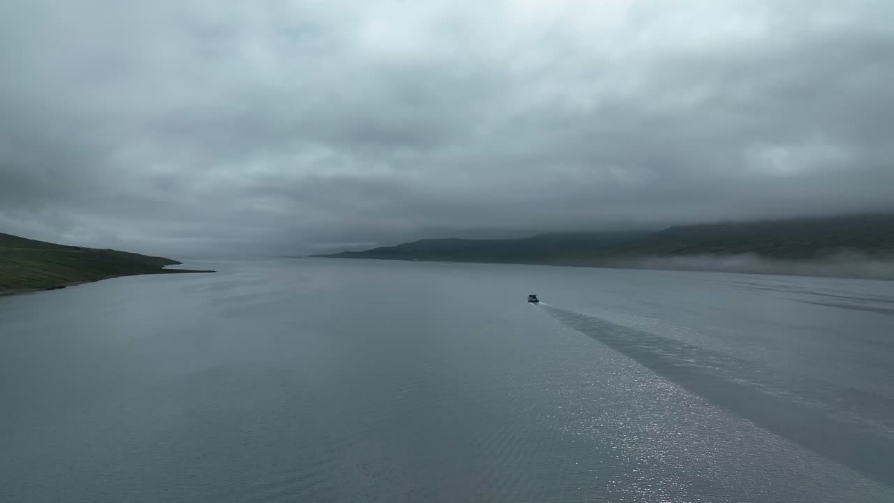 barco de pesca navegando en el idílico mar con el cielo nublado de faskrudsfjordur en el este de islandia