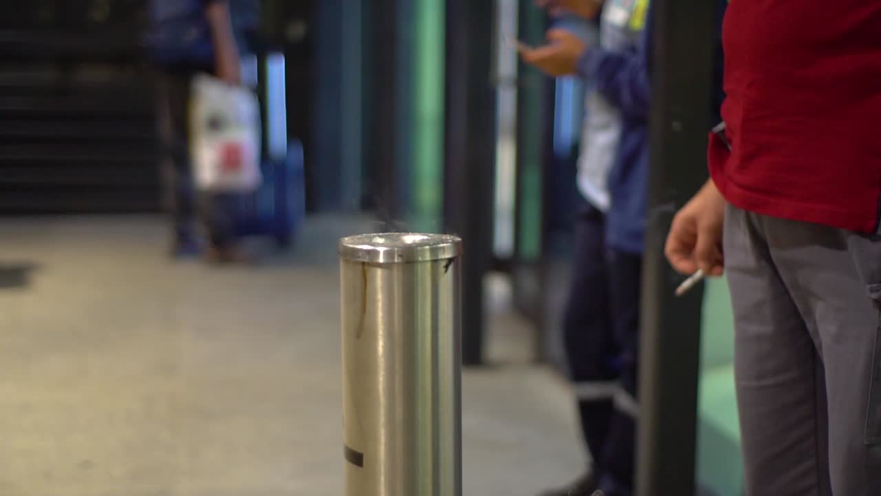 People at smoking room at an airport, holding cigarettes