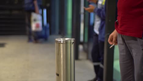 People-at-smoking-room-at-an-airport,-holding-cigarettes