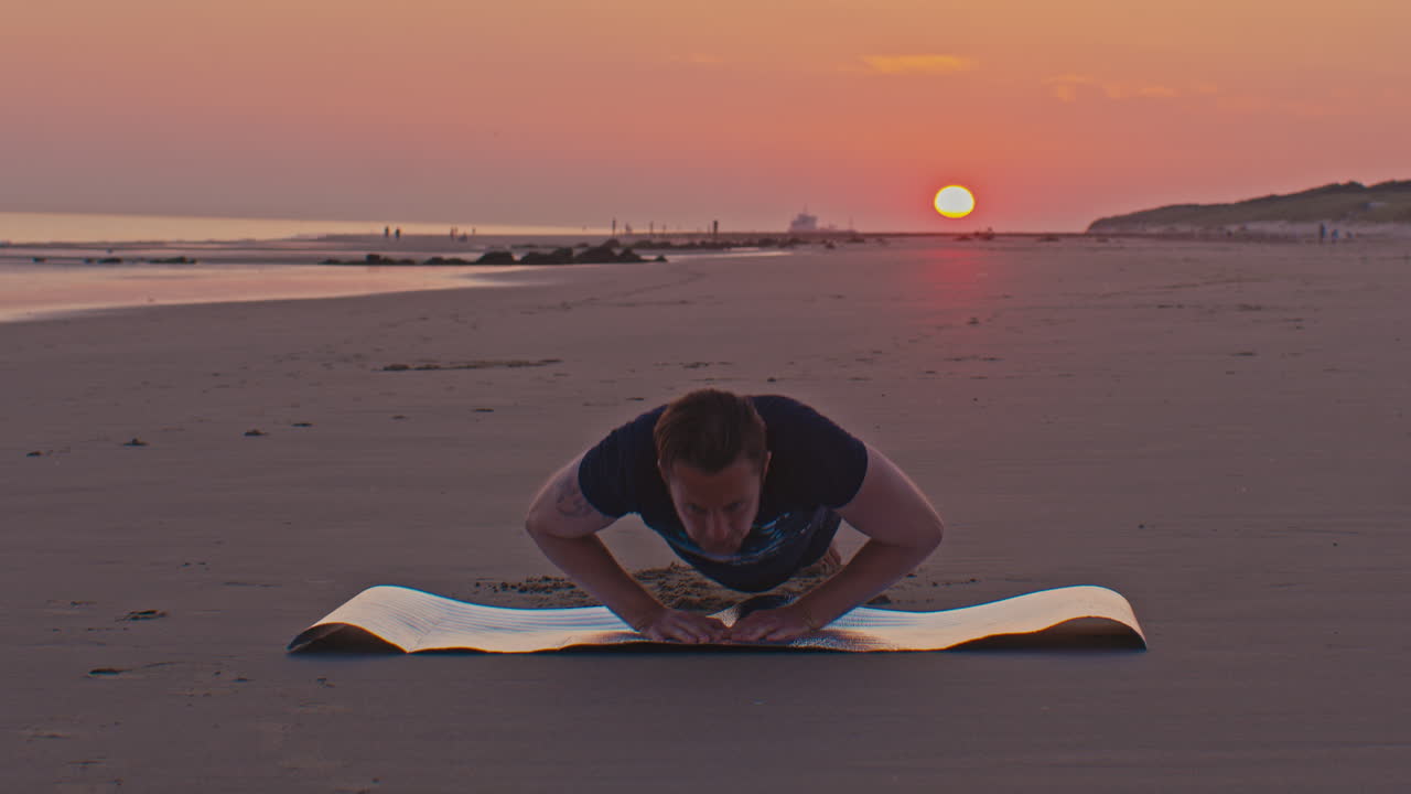 white slim caucasian european Dutch man male model does sunset training sports exercises narrow push-ups on the beach sand seashore in Netherlands North sea with setting sun on the background