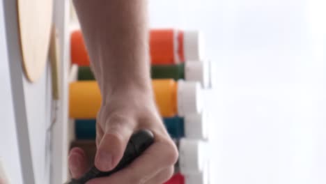 hands using a tool with various paint tubes in the background