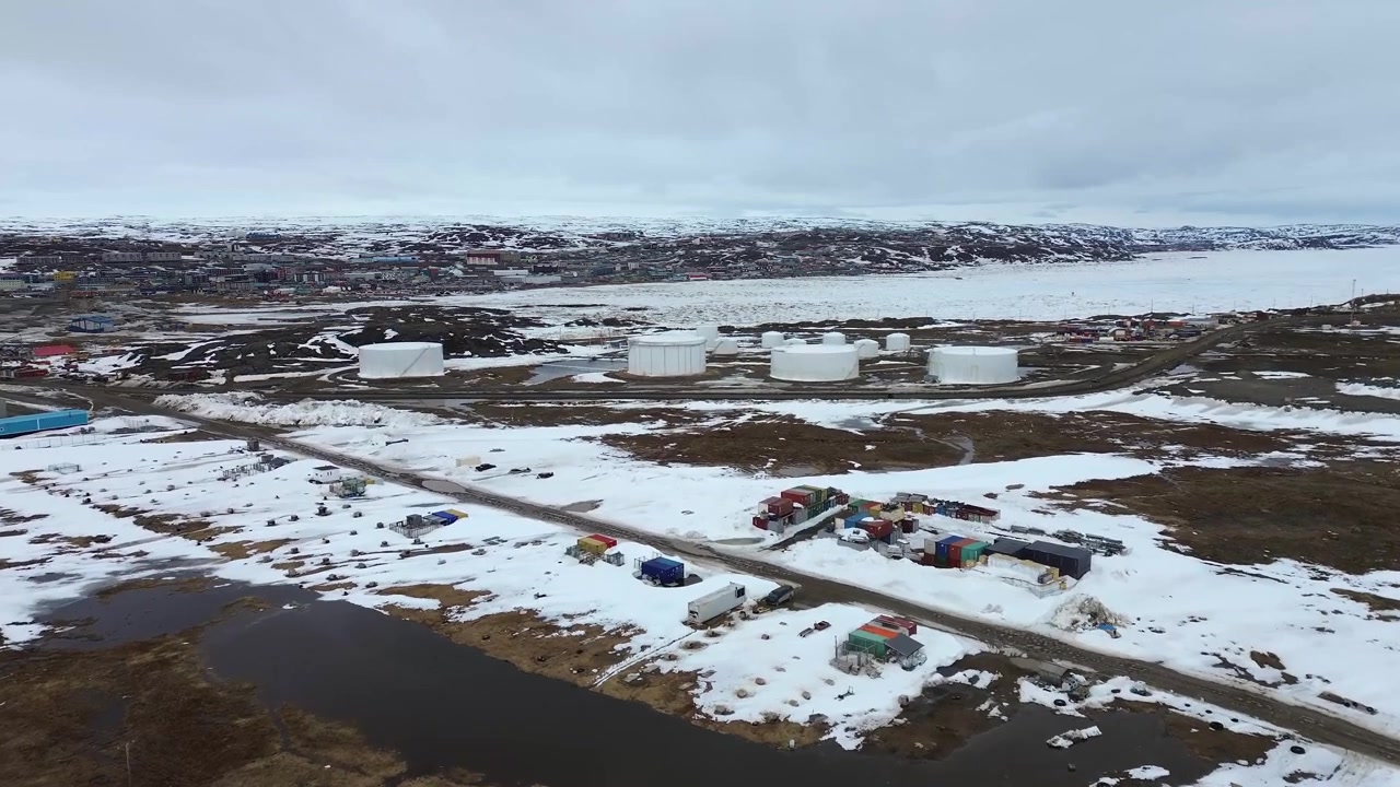 Drönarbild över stora vita petroleumlagringstankar i Iqaluit, Nunavut, under vårens snösmältning.