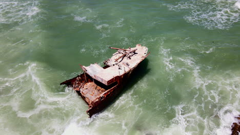 Órbita-Aérea-Alrededor-De-Un-Viejo-Naufragio-Oxidado-Que-Se-Encuentra-En-Aguas-Poco-Profundas-Rocosas,-Cabo-Agulhas