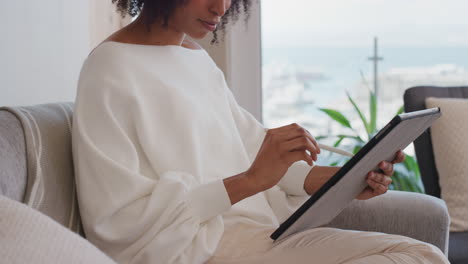 attractive young woman using digital tablet computer working at home browsing email messages with stylus pen enjoying mobile device technology