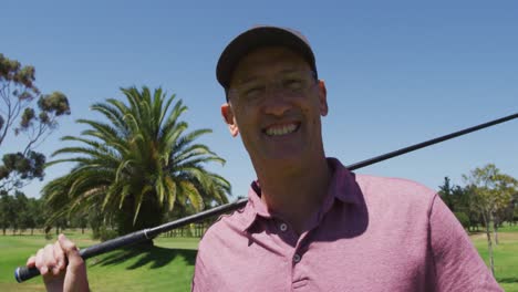 Portrait-of-caucasian-senior-man-with-golf-club-smiling-at-golf-course-on-a-bright-sunny-day