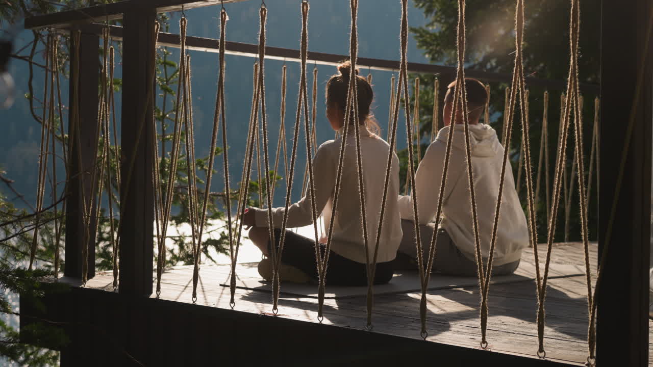 Couple enjoys sunrise meditating at glamping. Relaxed yoga lovers seek mind harmony at luxury eco resort. Woman and man sit in lotus poses outdoors