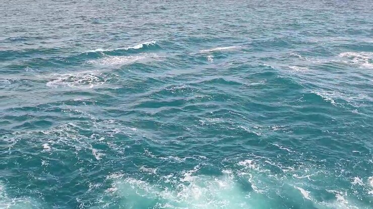 Acqua blu dell'oceano increspata con schiuma bianca