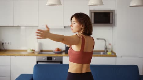 woman turn her arms, practicing yoga at home, rear view