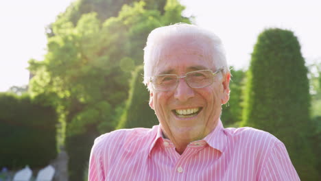 Happy-senior-man-smiling-to-camera-in-garden