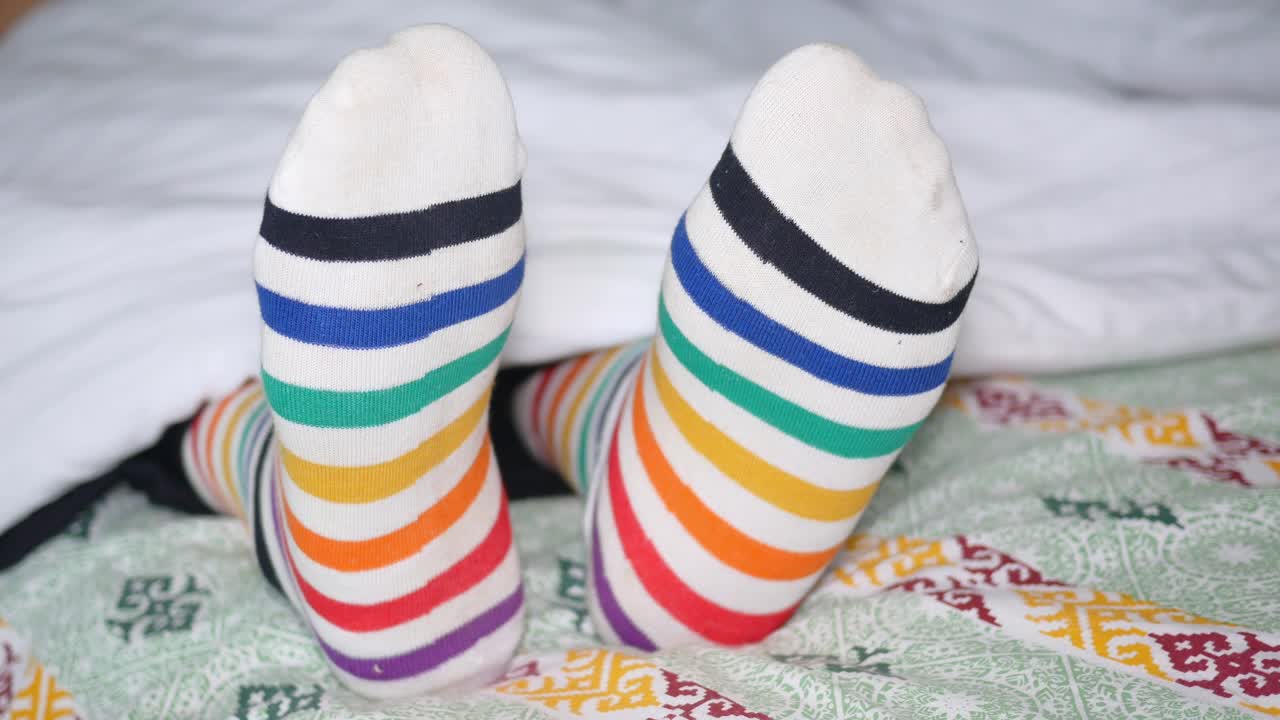 calcetines a rayas de colores en los pies en la cama