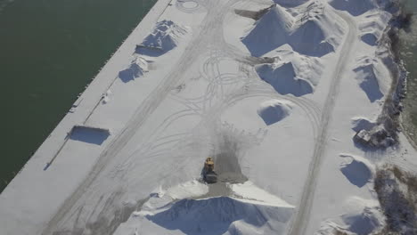 a loader at work loading sand covered with white snow in kingsville, ontario, canada - aerial shot